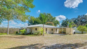 A single-story house with a covered porch, surrounded by a grassy yard and trees. - 'laurel on the Lakes' Floral City Escape w/ Canoe! (Floral City)