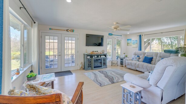 A spacious living room with a large sofa, a television mounted on the wall, and a ceiling fan. - 'laurel on the Lakes' Floral City Escape w/ Canoe! (Floral City)