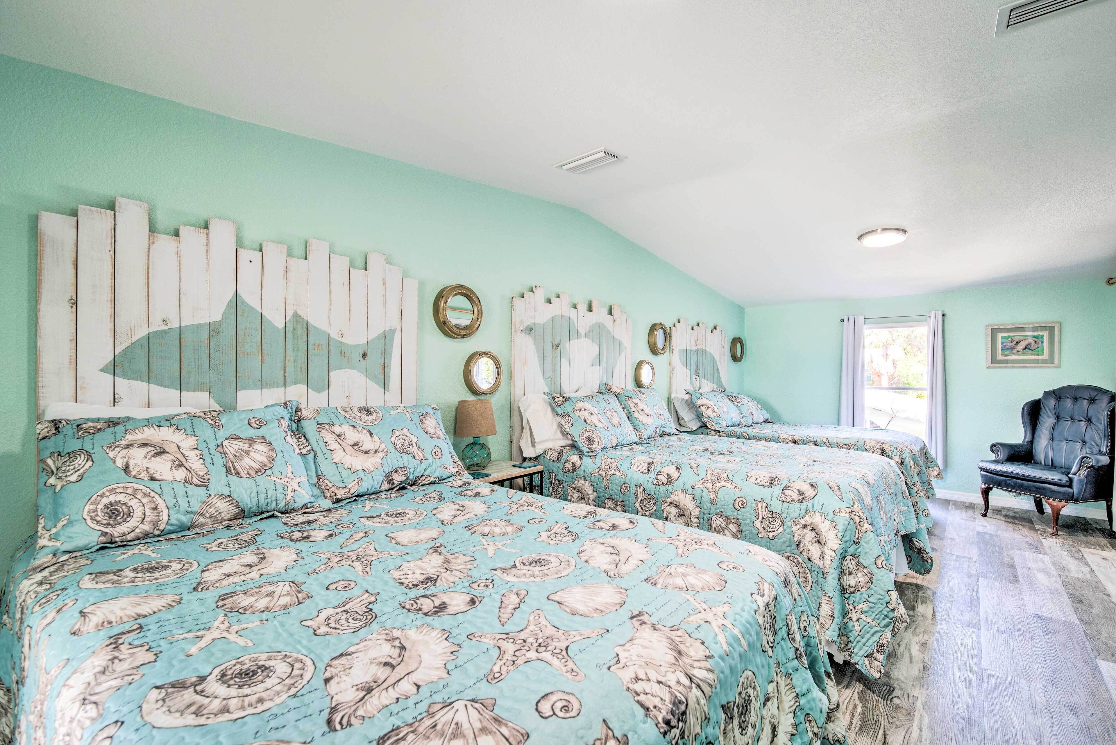 A bedroom with two beds, teal walls, and nautical-themed bedding.
