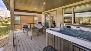 A wooden deck with outdoor seating, a hot tub, and a view of a house. - Furnished Deck & Hot Tub: Chic Granby Home! (Granby)