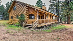 Une cabane en rondins dotée d’une véranda, de nombreuses fenêtres et d’une cheminée.