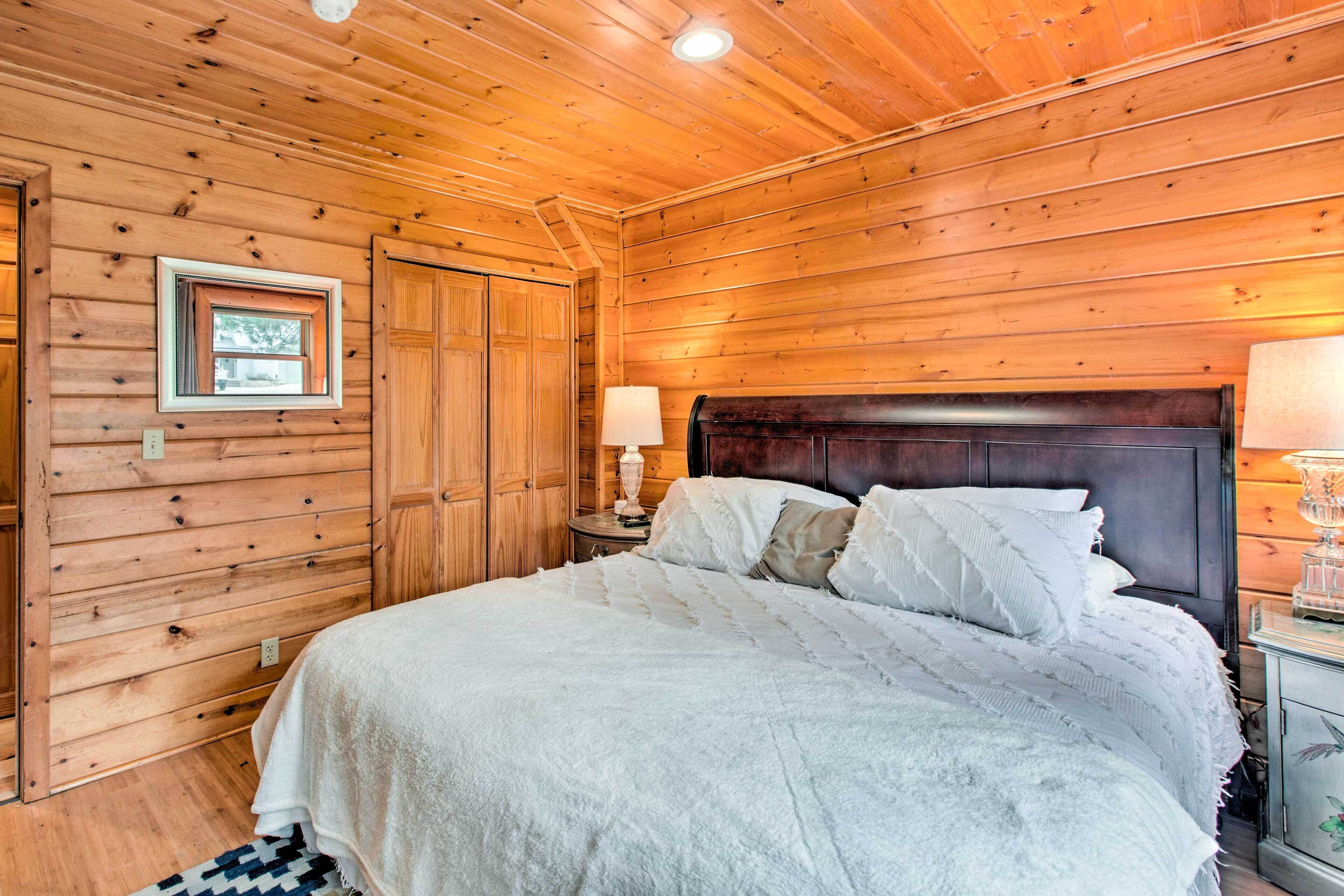 Un dormitorio con paneles de madera, una cama, una mesita de noche, una lámpara y un cuadro en la pared.