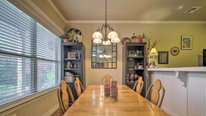 A dining room with a wooden table, chairs, a chandelier, and built-in bookshelves.