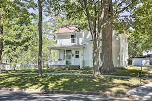 A two-story house with a porch and a large tree in front. - Family-friendly Menomonie Retreat: Walk to Town! (Menomonie)