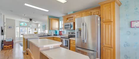 Una cocina moderna con armarios de madera, electrodomésticos de acero inoxidable y una isla central.