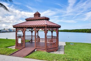 A gazebo with a metal roof and wooden railings, situated on a grassy area by a lake. - Nettles Island Jensen Beach Home: Walk to Ocean! (Jensen Beach)