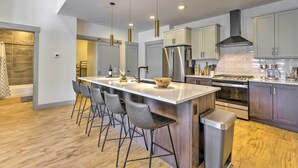 A modern kitchen with a central island, bar stools, stainless steel appliances, and light-colored cabinetry. - Condo w/ Mountain Views in Heart of Downtown! (Winter Park)