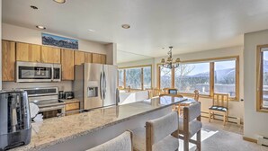 A modern kitchen with granite countertops, stainless steel appliances, wooden cabinets, and a large island with bar stools. - Condo w/ Views & Hot Tub Access in Silverthorne! (Silverthorne)