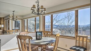A dining area with a large window, a chandelier, and wooden chairs. - Condo w/ Views & Hot Tub Access in Silverthorne! (Silverthorne)