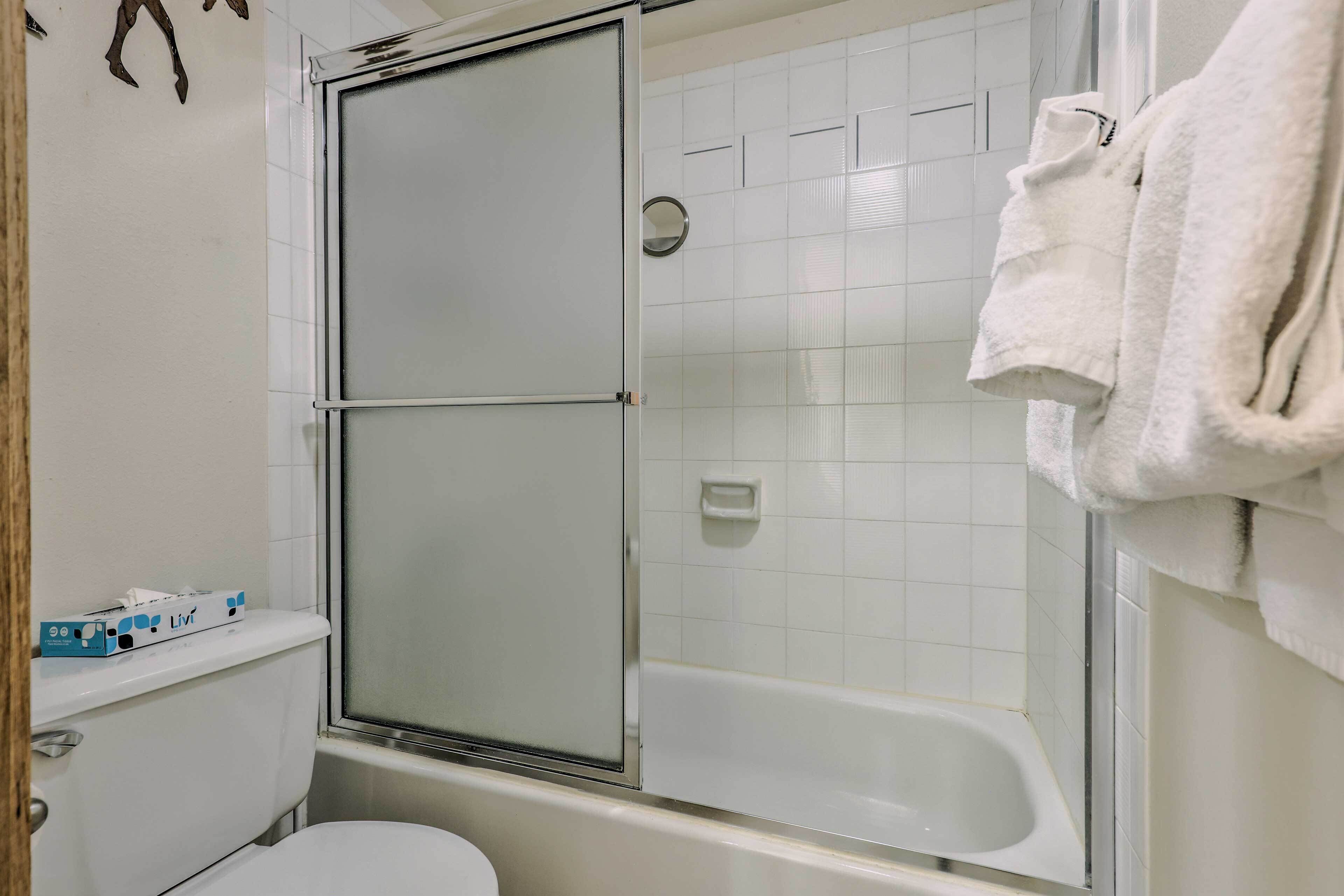 A bathroom with a glass shower enclosure, a white bathtub, and a toilet.