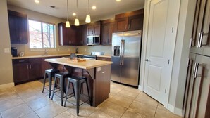 A kitchen with dark wooden cabinets, a stainless steel refrigerator, and a large window. - Entrada at Moab 652 (Moab)