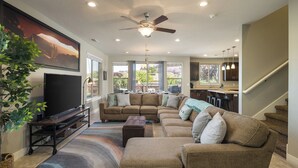 A spacious living room with a sectional sofa, a flat-screen TV, a ceiling fan, and a large window offering a view of the outdoors. - Entrada at Moab 652 (Moab)