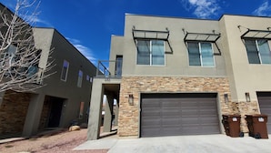 A modern two-story building with a stone facade, a garage, and a balcony. - Entrada at Moab 652 (Moab)