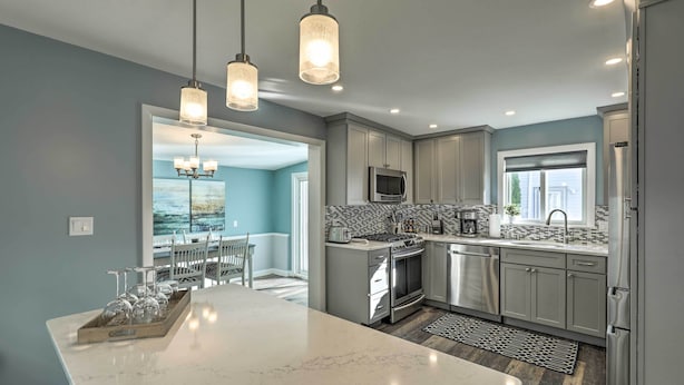 A modern kitchen with a large island, stainless steel appliances, and pendant lighting. - Pet-friendly Revere Getaway, Steps From the T! (Revere)