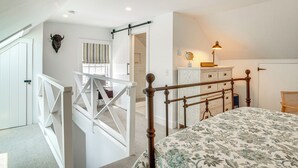 Une chambre à coucher avec un lit, une commode, une lampe et une horloge fixée au mur.