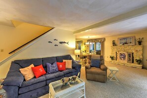 Un salon avec un canapé bleu foncé, un fauteuil marron et une table basse en verre.