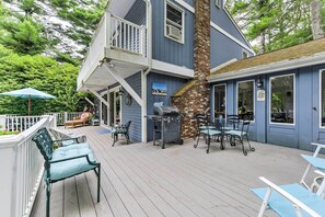 Une maison bleue avec une terrasse, un coin salon extérieur et un barbecue.
