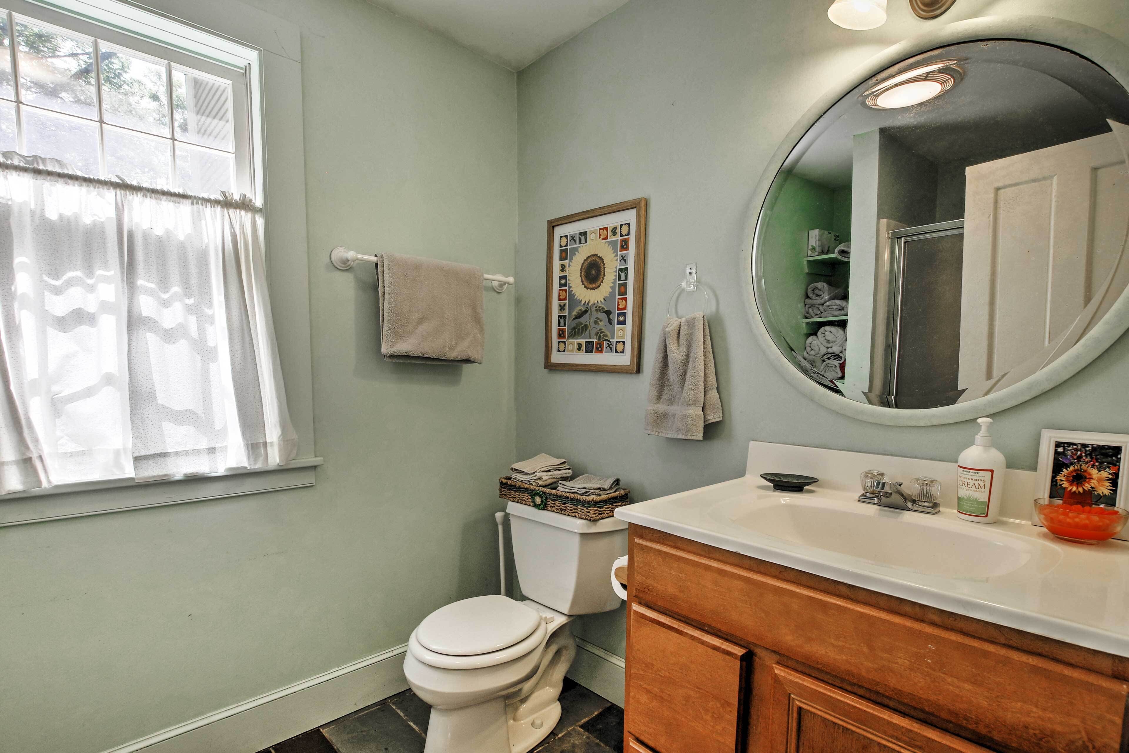 A bathroom with a toilet, a sink, a mirror, and a window with curtains.