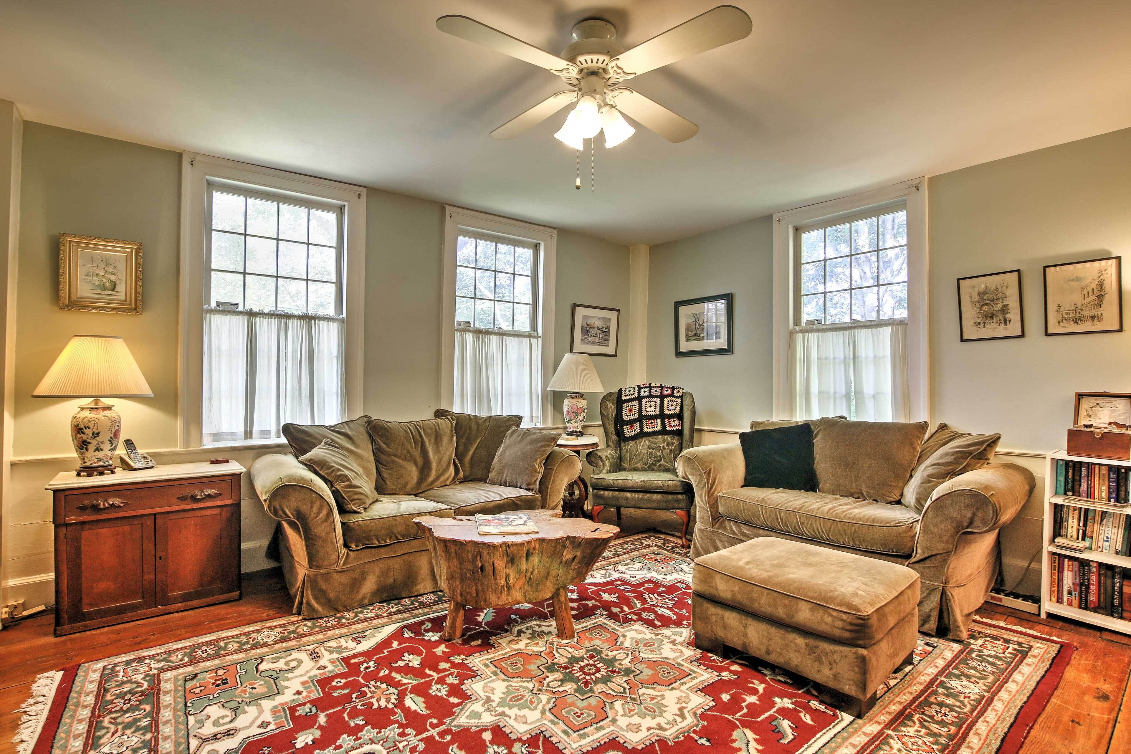 A living room with two sofas, a coffee table, a bookshelf, and a ceiling fan.