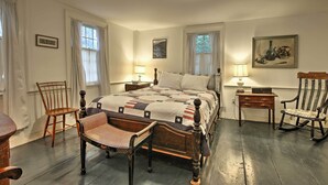 A traditional bedroom with a wooden bed, a rocking chair, a chair with a woven seat, and a small table with a lamp. - Historic Huntington Home - Walk to Westfield River (Huntington)