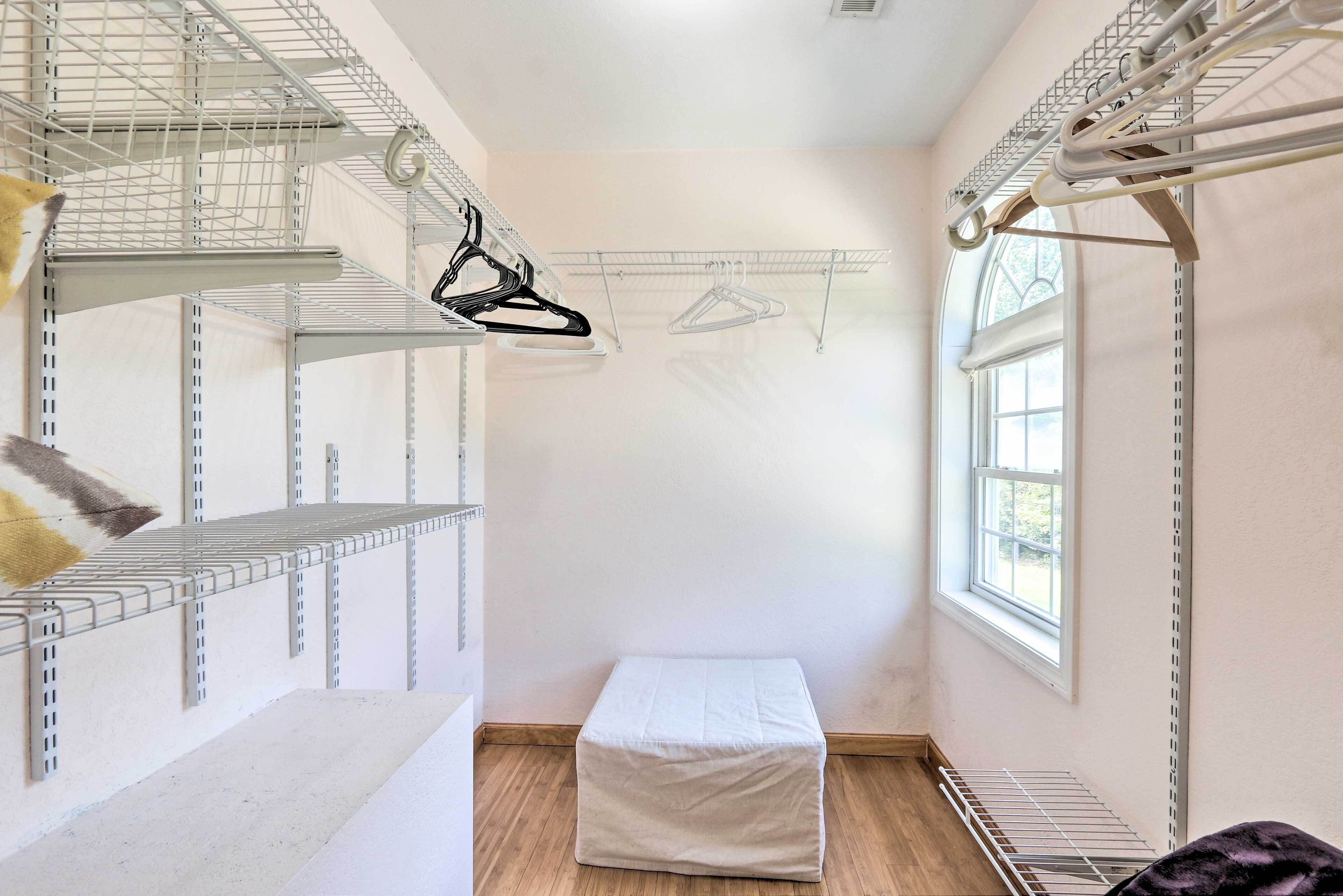 A room with metal shelving units, a bench, and a window.