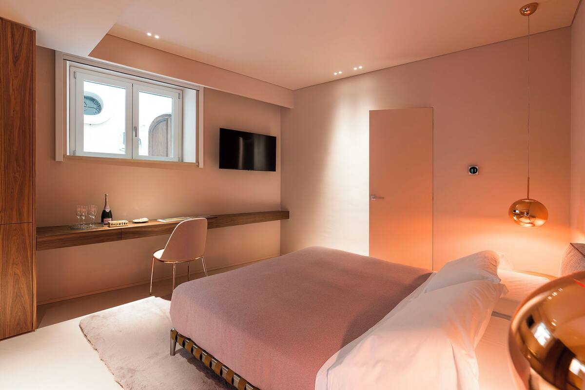 Un dormitorio moderno con cama, escritorio, silla, televisor y armario.