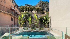 A rooftop pool with glass railings, potted plants, and a view of a hillside. - Taormina Infinity Suites (Taormina)
