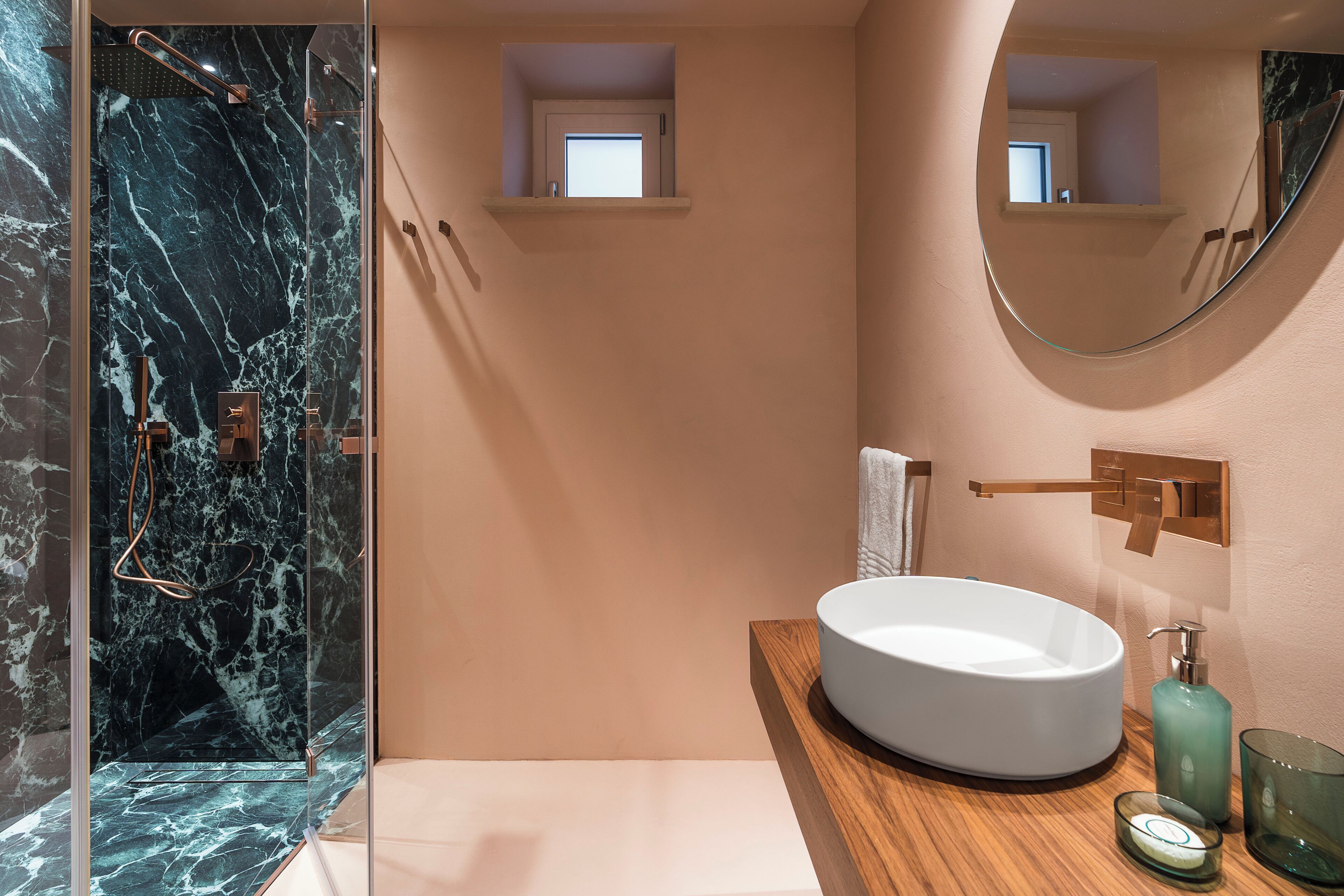 A modern bathroom with a glass-enclosed shower, a round sink, and a mirror above the sink.