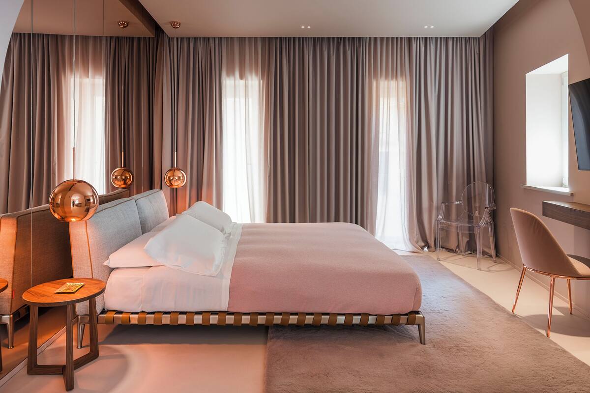 Un dormitorio moderno con una cama grande, una mesita de noche, una silla y un escritorio con su propia silla.