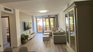 Ein geräumiger Wohnbereich mit Esstisch, Sofa und Fernseher.