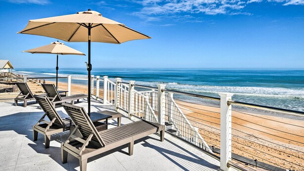 Eine Strandterrasse mit Liegestühlen und Sonnenschirmen mit Blick auf den Ozean.