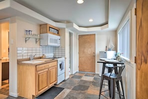 A kitchen with a wooden countertop, white cabinets, a microwave, and a stove. There is a dining area with a table and chairs. - Brookings Vacation Rental Studio - Walk to Town! (Brookings)