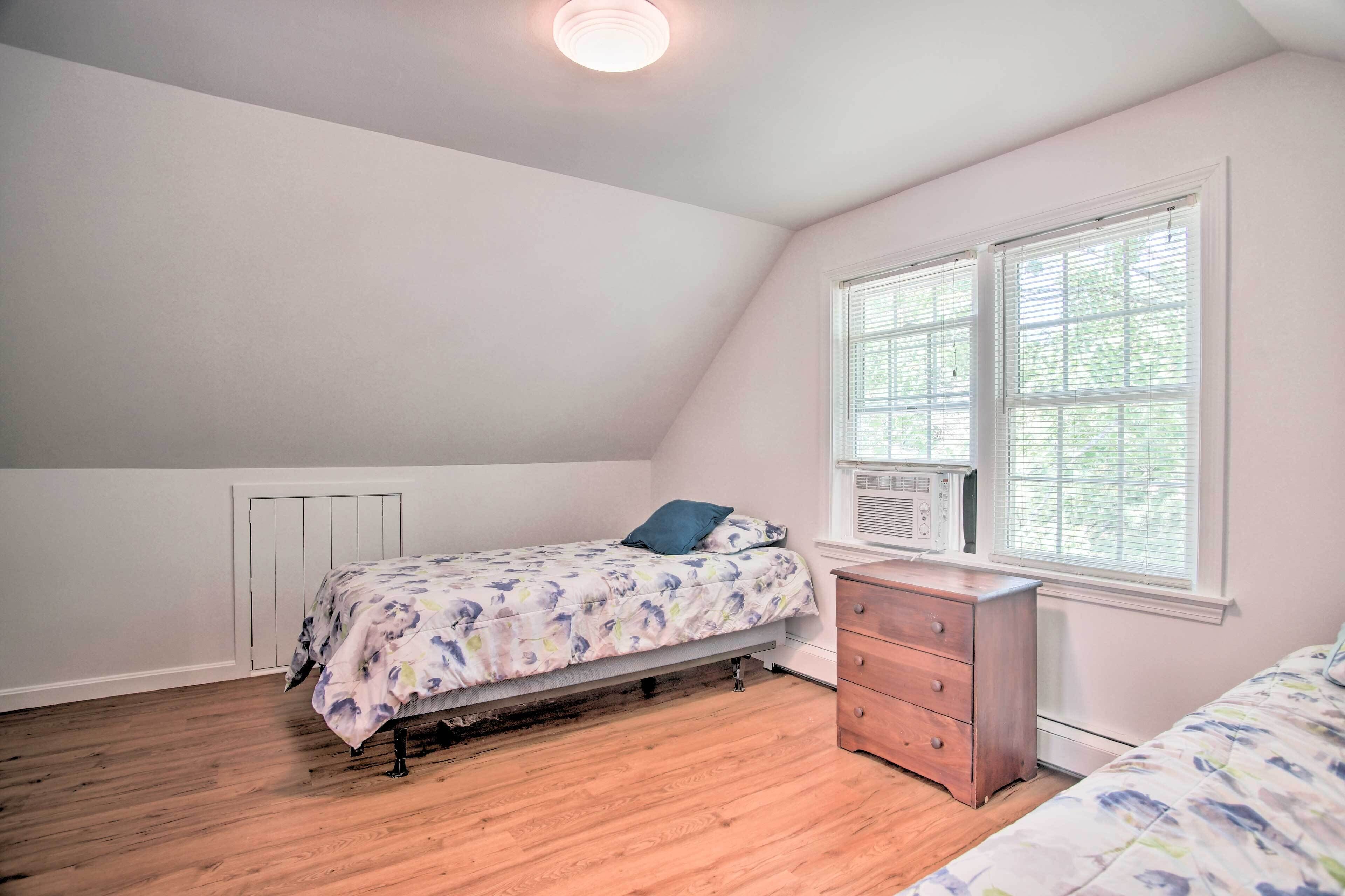 A bedroom with a single bed, a dresser, and a window with blinds.