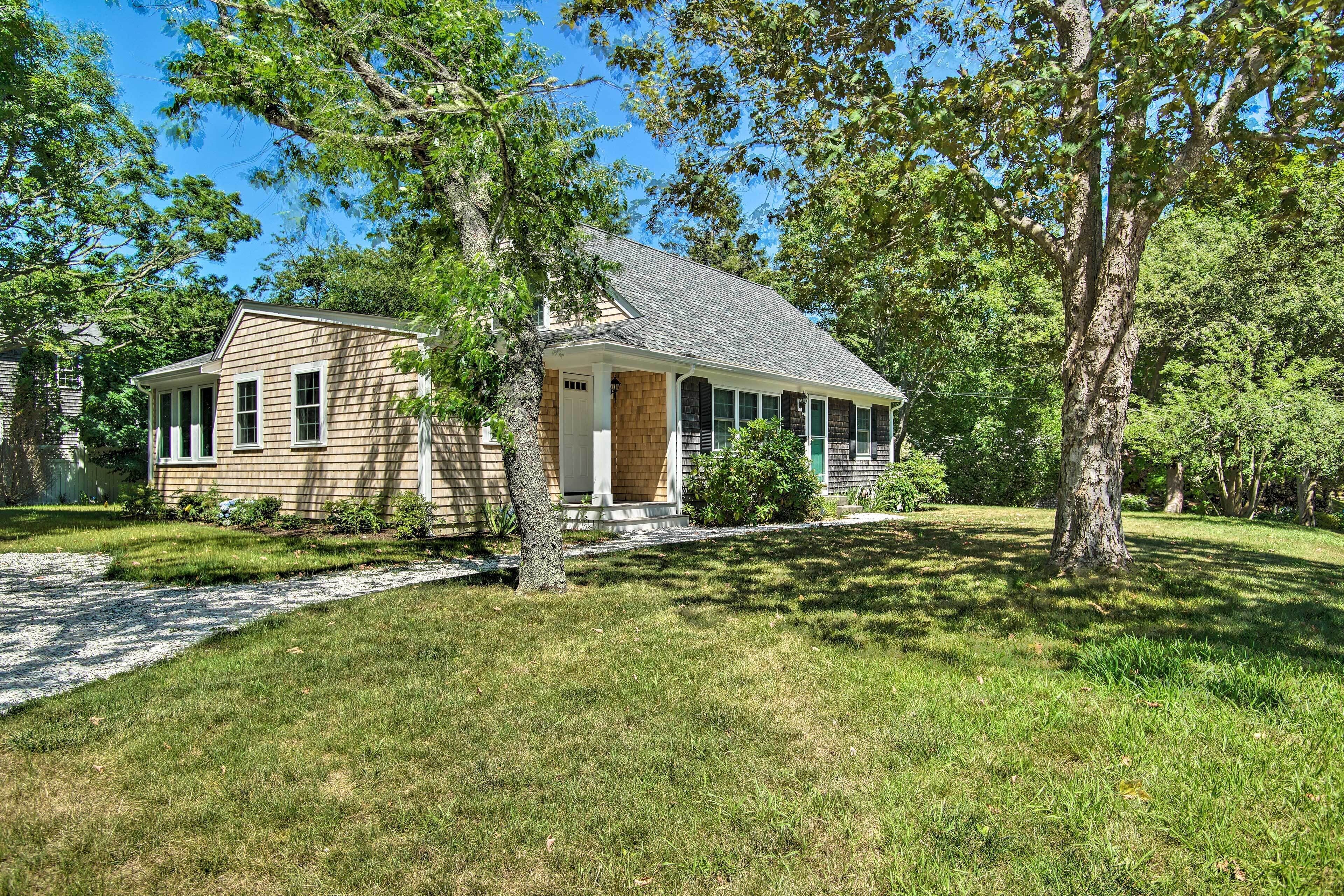 A two-story house with a front porch, surrounded by trees and a well-maintained lawn.