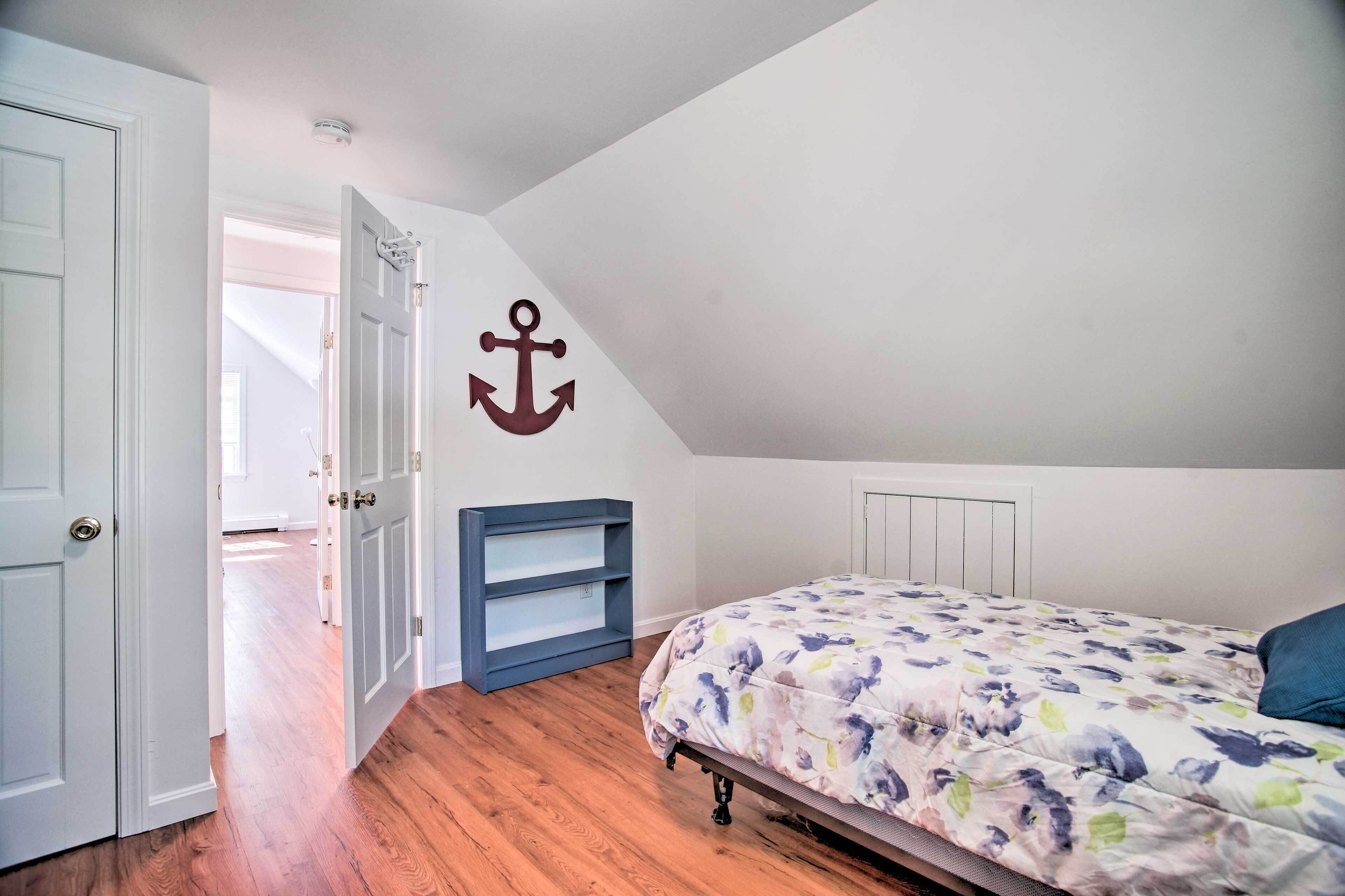 Un dormitorio con cama, armario y una decoración de ancla en la pared.