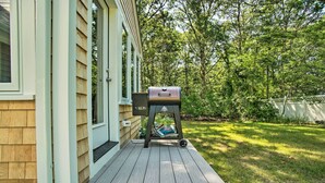 Une terrasse en bois avec un barbecue et un sac de charbon de bois.