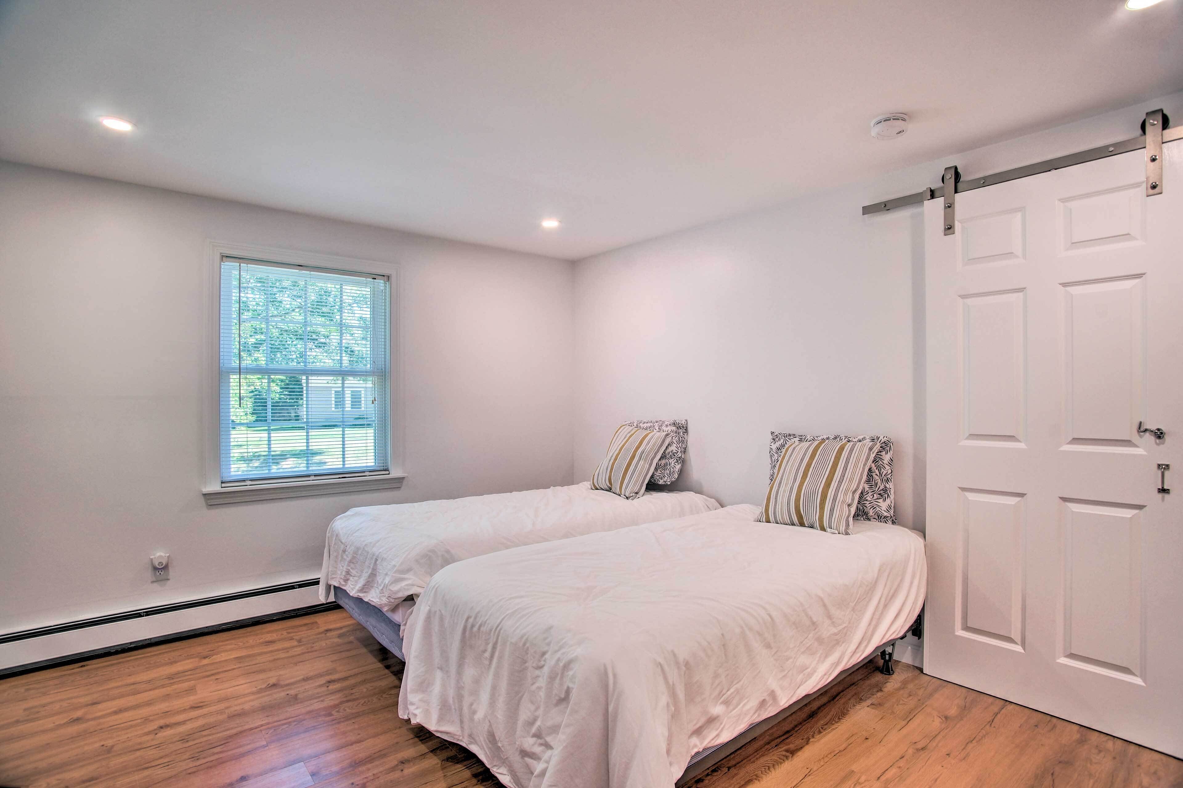 A bedroom with two beds, a window, and a sliding door.