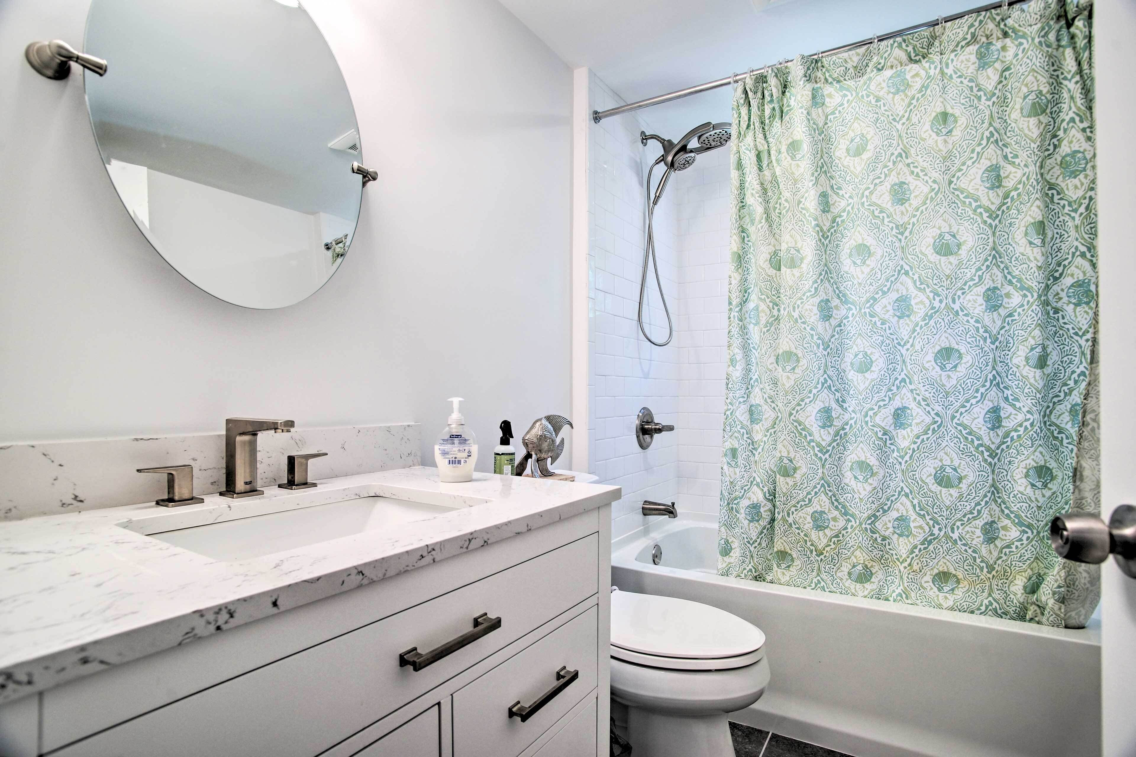 A bathroom with a white marble sink, a toilet, and a bathtub.