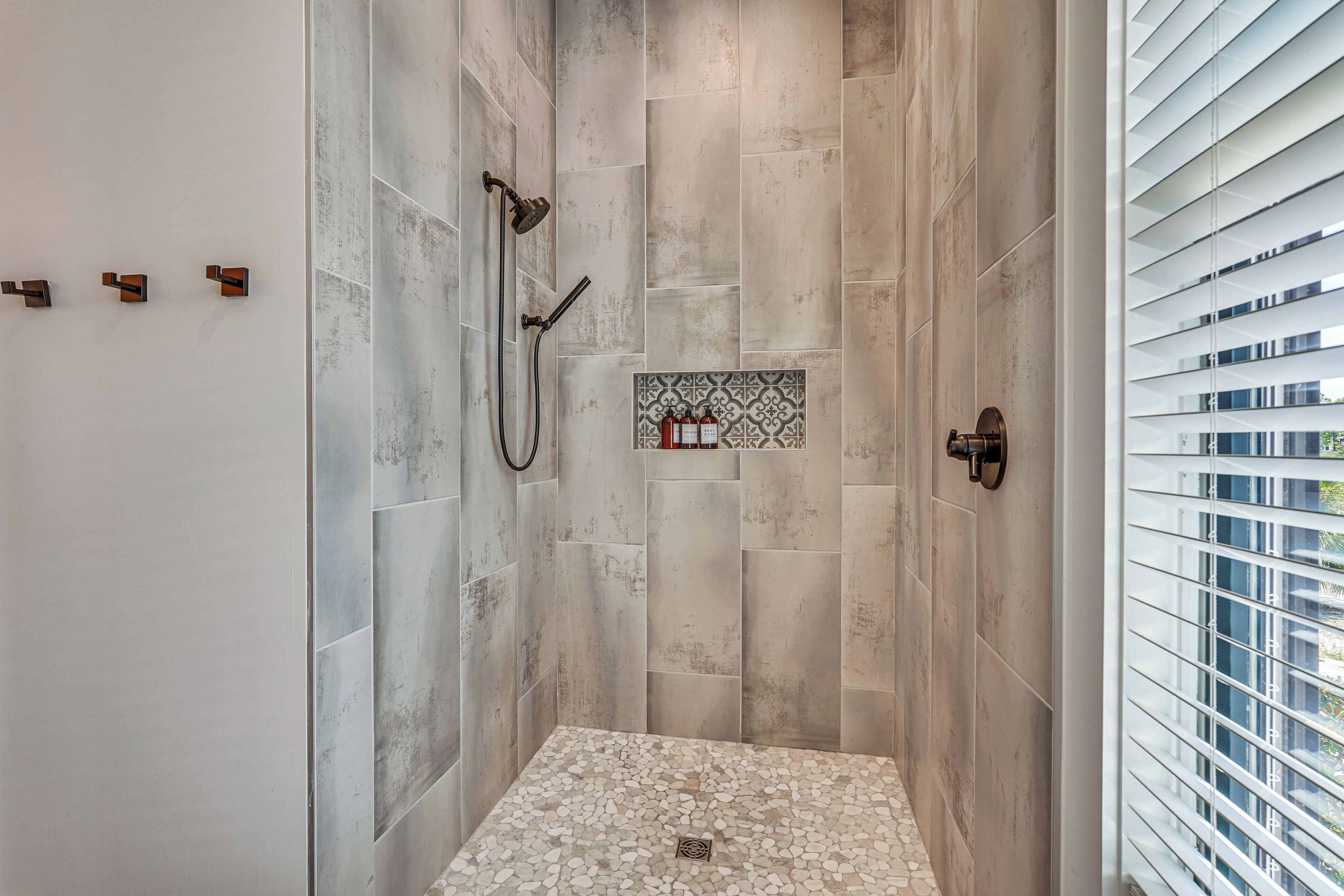 A shower with a tiled floor and a wall-mounted showerhead.
