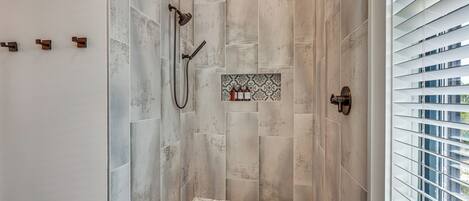 A shower with a tiled floor and a wall-mounted showerhead.