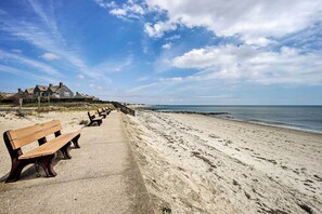 Ein Strand mit Holzbanken und einer Reihe von Häusern im Hintergrund.