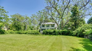 A large, light green house with a spacious lawn and dense trees in the background. - Mattapoisett Home on 7 Acres w/ Private Beach! (Mattapoisett)