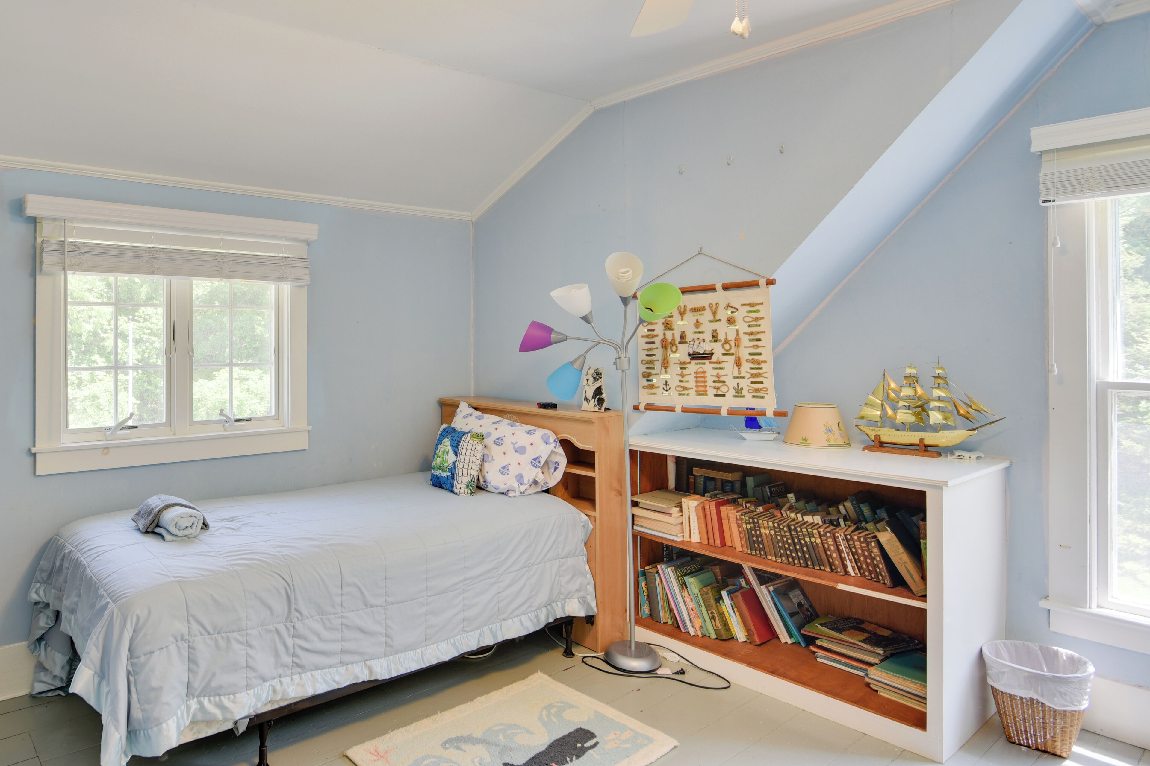 Ein Schlafzimmer mit Bett, Bücherregal, Schreibtisch und Fenster.