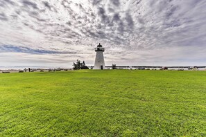 A lighthouse on a grassy field with a cloudy sky. - Mattapoisett Home on 7 Acres w/ Private Beach! (Mattapoisett)
