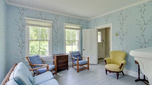A room with light blue walls, white wooden flooring, and two windows. There are three wooden chairs with blue cushions and a yellow armchair. A white door is visible in the background. - Mattapoisett Home on 7 Acres w/ Private Beach! (Mattapoisett)