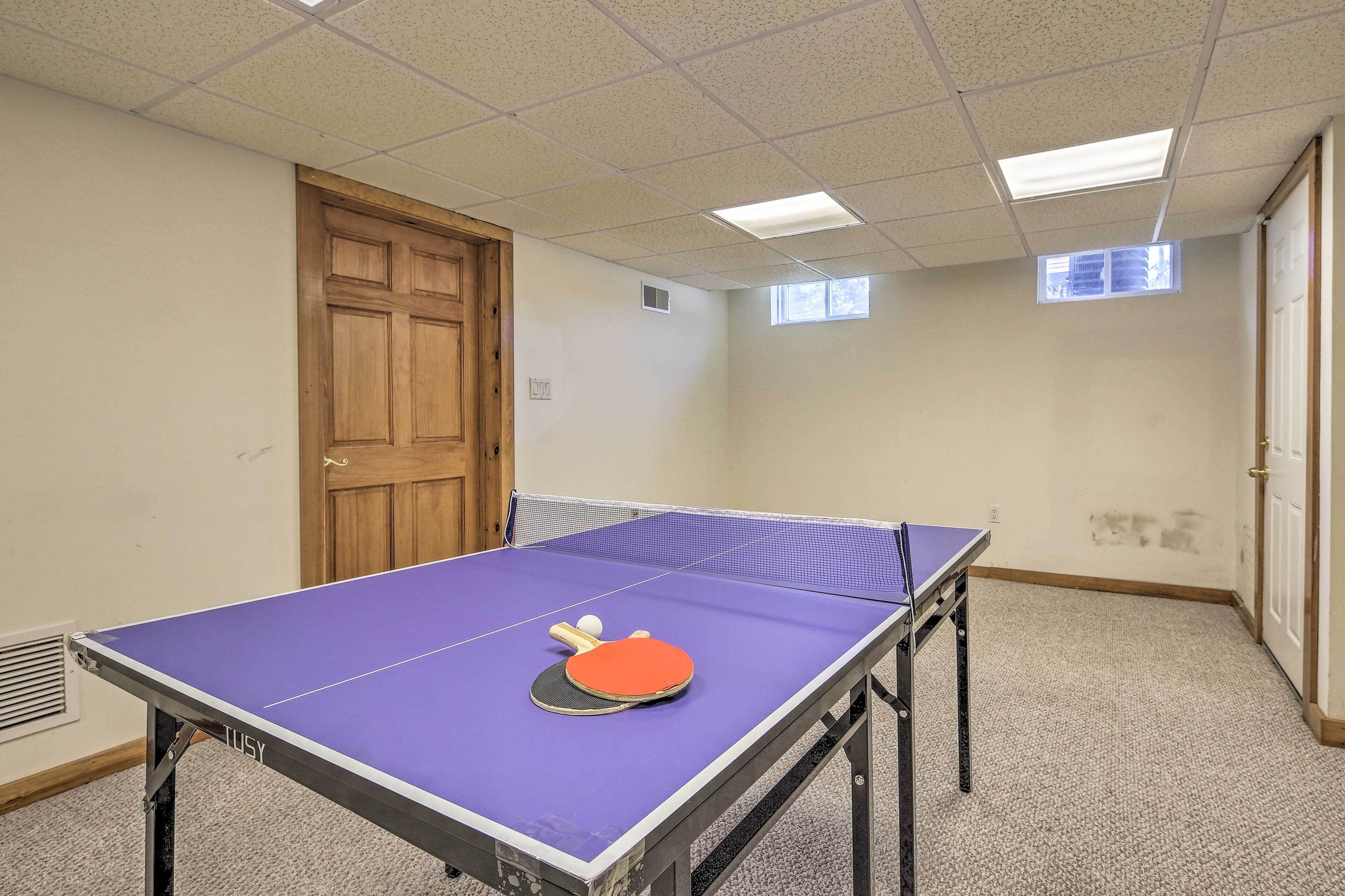 A room with a ping pong table, a door, and a window.