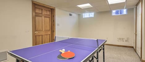 A room with a ping pong table, a door, and a window.
