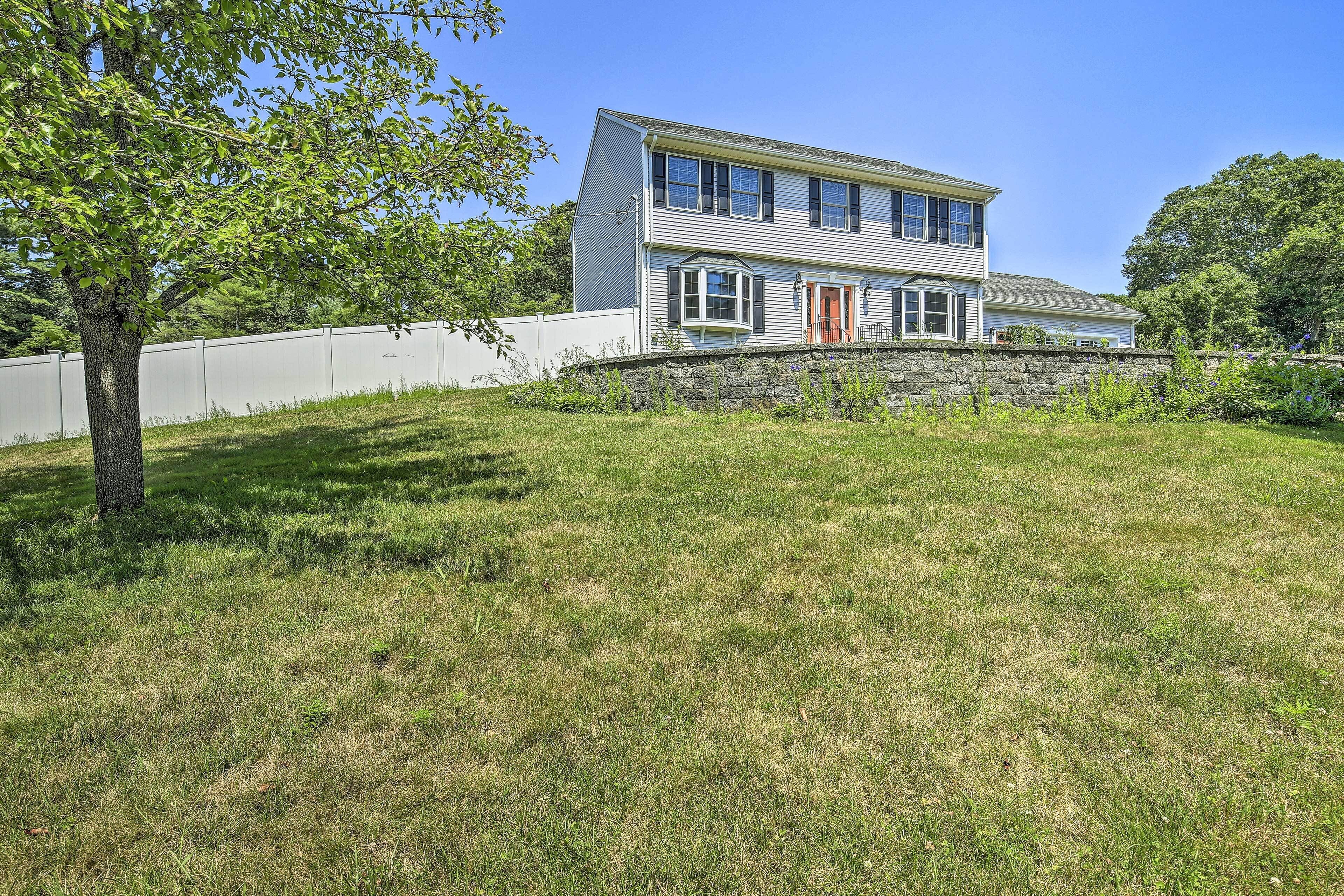 A two-story house with a stone wall and a grassy yard.