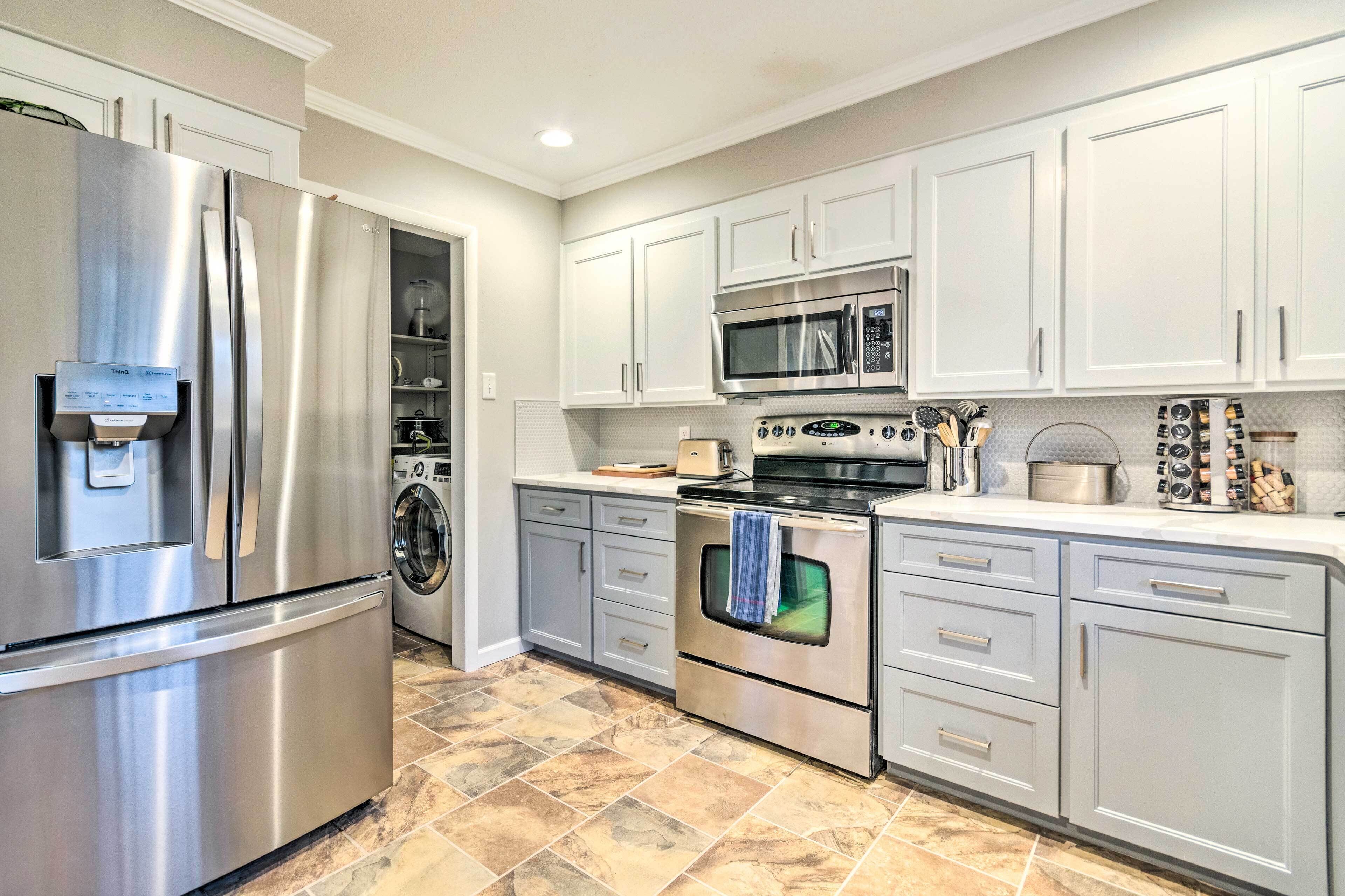 A modern kitchen with stainless steel appliances, white cabinets, and a tiled floor.