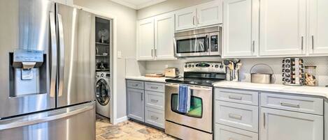 A modern kitchen with stainless steel appliances, white cabinets, and a tiled floor.